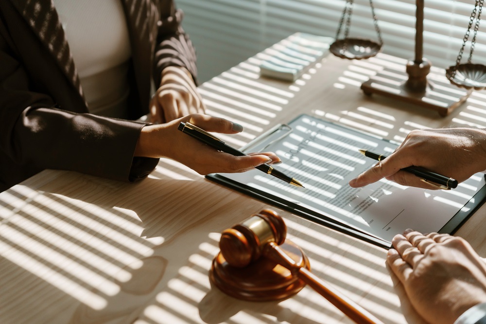 lawyer is pointing with a pen where to sign a legal document during a meeting in the office